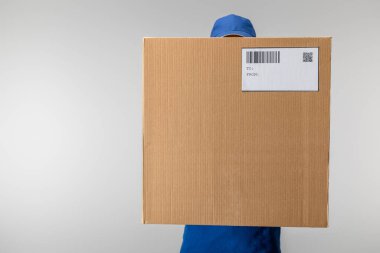 Üniformalı teslimatçı elinde QR kodu ve barkod olan karton kutu tutuyordu.