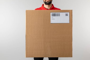 Gri kart üzerindeki barkod ve qr kodlu kurye paketinin kırpılmış görünümü