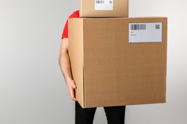 Elinde barkodlu kutular ve gri kartların QR kodları olan teslimatçı.