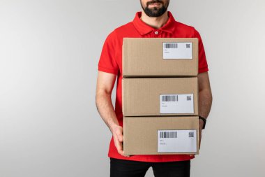 Sakallı kuryenin elinde barkodlu kutular ve gri renkli kartların QR kodları vardı.