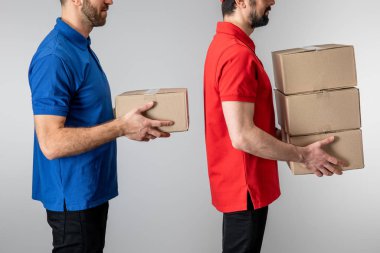 Gri üzerinde karton kutular taşıyan teslimatçıların yan görüntüsü
