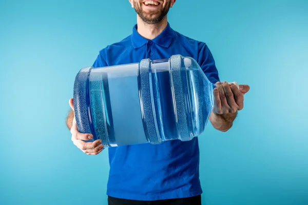 Vista Recortada Del Mensajero Sonriente Sosteniendo Agua Embotellada Aislada Azul — Foto de Stock