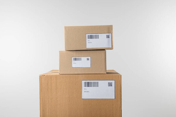 Упакованные картонные коробки со штрих-кодами и qr-кодами на картах, изолированных на сером
