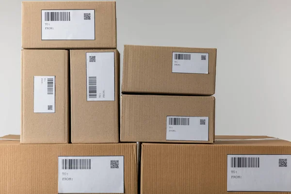 Stacked cardboard boxes with barcodes and qr codes isolated on grey