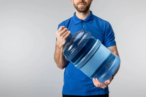 ブルーに隔離されたボトル入りの水を保持する宅配便の作物ビュー — ストック写真