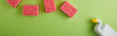 panoramic shot of pink sponges and bottle with toilet cleaner on green