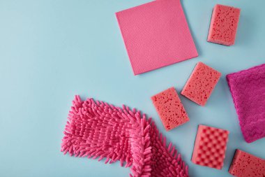Pembe paçavraların ve süngerlerin üst görüntüsü mavi üzerine ev temizliği için.