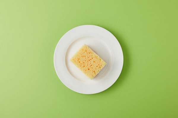 верхний вид тарелки и желтая губка для мытья посуды на зеленый
