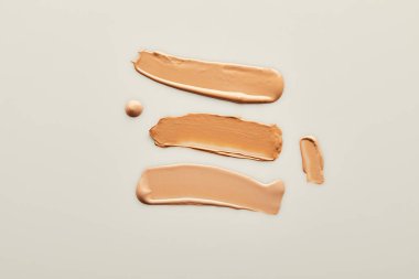 Gri arkaplanda ton kremi fırça darbelerinin üst görünümü