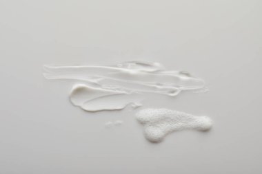 Top view of gel and cosmetic cream brushstrokes with soap foam on grey background clipart