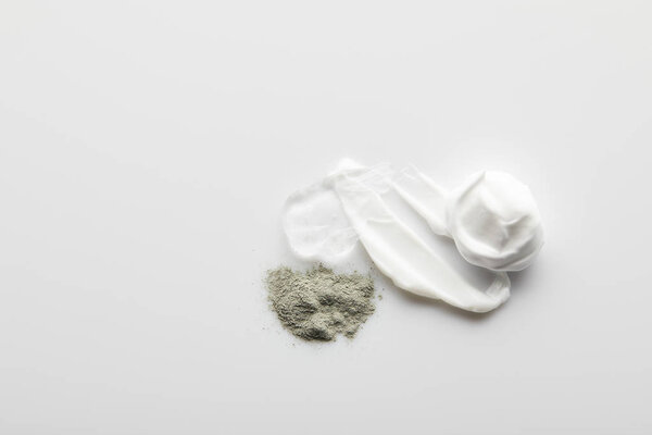 Top view of cosmetic cream brushstrokes, gel, clay powder on grey background