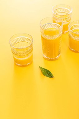 Yeşil yaprağın yanında taze, lezzetli sarı smoothie bardakları