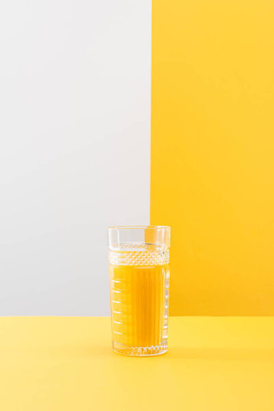 glass of fresh delicious yellow smoothie on grey and yellow background