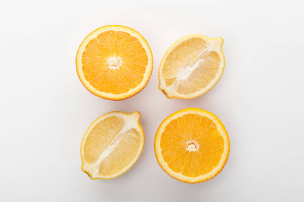 Top view of orange and lemon halves on white background