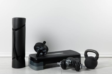 Siyah fitness paspası, adım platformu ve evde spor malzemeleri.  