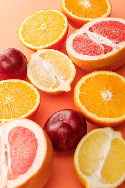 Selective focus of citrus fruits halves and apples on orange background