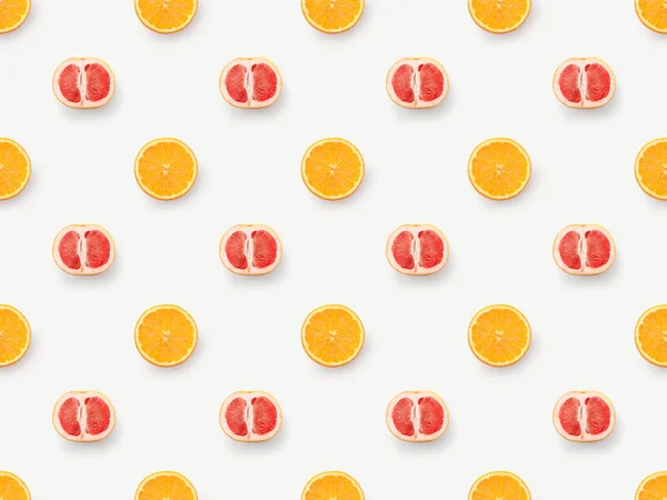 Top view of grapefruits halves and orange slices on white background