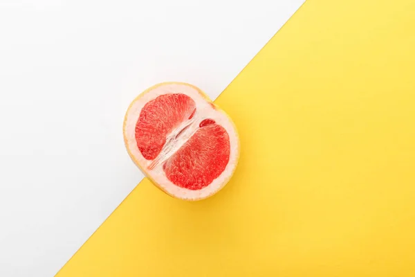 黄色と白の背景にグレープフルーツの半分のトップビュー — ストック写真