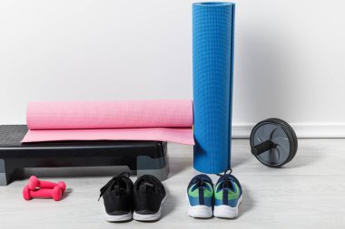 adım platformu, fitness paspasları ve spor kıyafetleri evde yerde. 