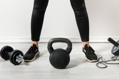 Kettlebell ve spor eşyalarıyla evde duran atletik kız manzarası. 