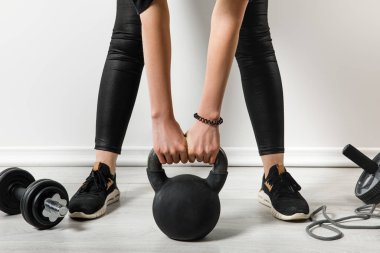 Spor malzemeleriyle evde kettlebell kullanan atletik kadın antrenmanı manzarası.