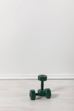 two green dumbbells for fitness on floor clipart