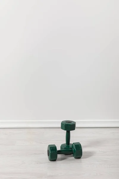 two green dumbbells for fitness on floor