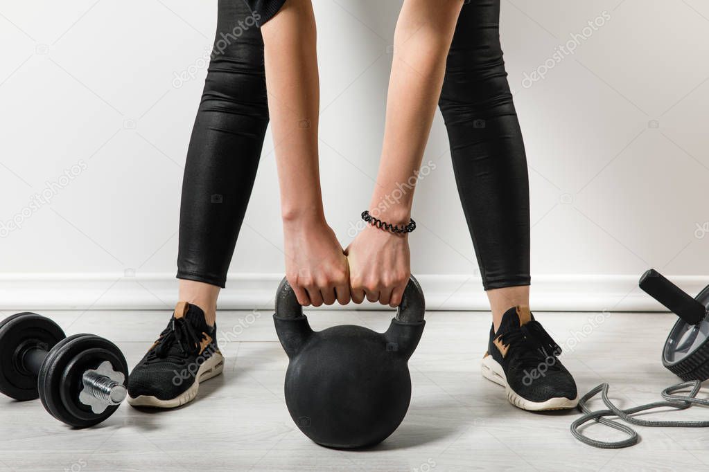 cropped view of athletic woman training with kettlebell at home with sports stuff