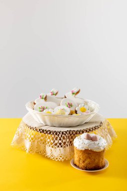 Hasır sepetteki lezzetli kurabiyeler, güvertede, gri renkli paskalya pastasının yanında.