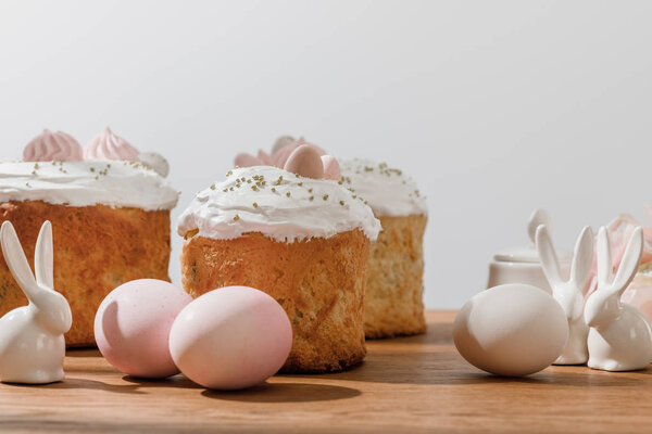 Декоративные кролики, куриные яйца, сахарная чаша и пасхальные торты, изолированные на сером
