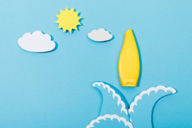 Kağıdın üst görüntüsü mavi üzerine güneş kremi ile deniz dalgalarını, bulutları ve güneşi keser. 