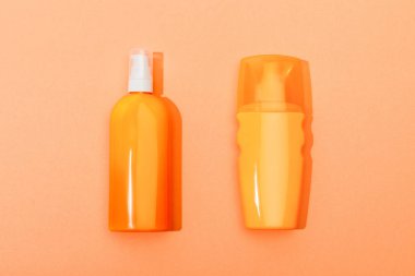 Top view of dispenser bottles of sunscreen on orange background clipart