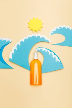 Top view of paper cut sun and sea waves with dispenser bottle of sunscreen on beige clipart