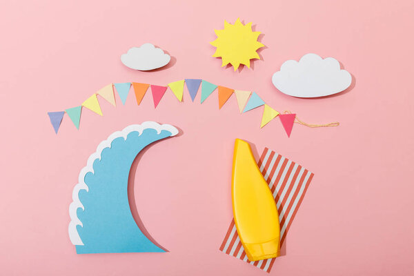 Top view of paper cut summer beach with surfboard and sunscreen on pink background