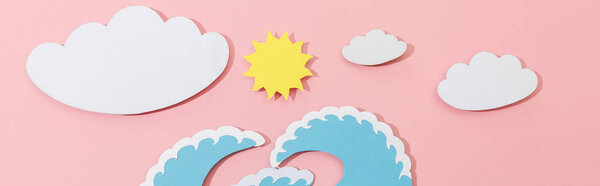 Top view of paper cut sea waves, clouds and sun on pink background, panoramic shot