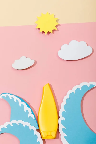 ピンクとベージュの背景に日焼け止めのチューブと紙カットビーチのトップビュー — ストック写真
