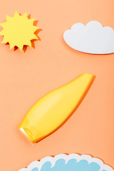 紙カット太陽のトップビュー オレンジに日焼け止めのチューブと雲と海の波 — ストック写真