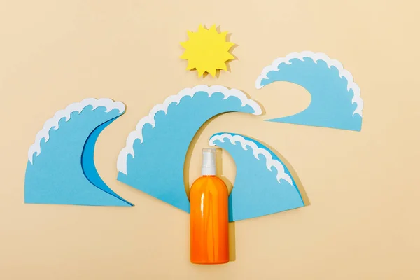 紙カット太陽とベージュの背景に日焼け止めのディスペンサーボトルと海の波のトップビュー — ストック写真