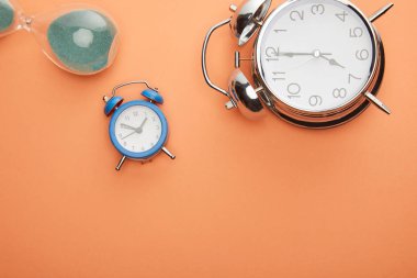 Şeftali arkaplanındaki alarm saatlerinin ve kum saatlerinin üst görünümü