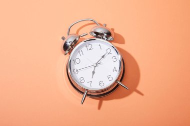 top view of classic alarm clock on peach background clipart