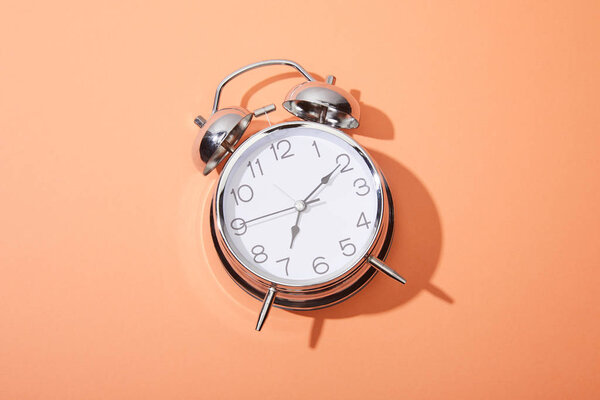 top view of classic alarm clock on peach background