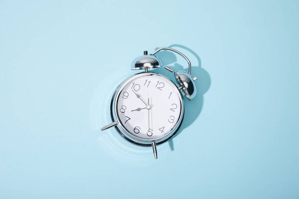 top view of classic alarm clock on blue background