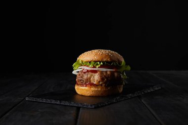 Siyah üzerine izole edilmiş koyu ahşap kesme tahtasına hamburger. 