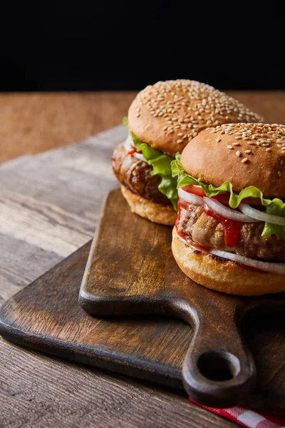Dwa Hamburgery Drewnianych Deskach Rozdrabniających Izolowane Czarno — Zdjęcie stockowe
