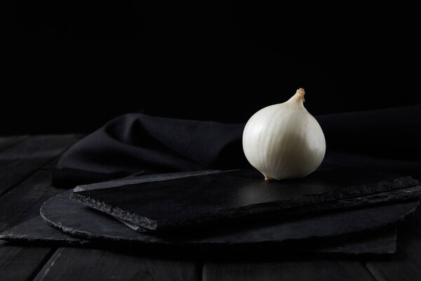 Whole white onion on black chopping boards isolated on black 