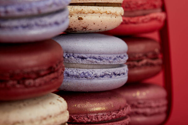 stack of assorted delicious colorful french macaroons on red background