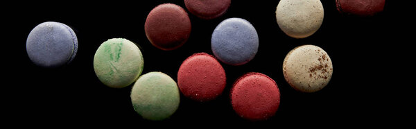 top view of assorted delicious colorful french macaroons isolated on black, panoramic shot