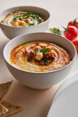 Gri arka planda lezzetli humus olan kâseleri kapat