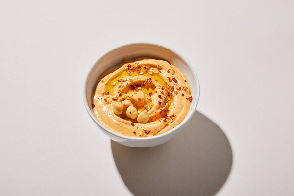 Закрыть вид на чашу с хумусом на сером фоне
