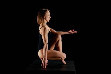 Siyah elbiseyle yoga yapan güzel bir kadının yan görüntüsü. 
